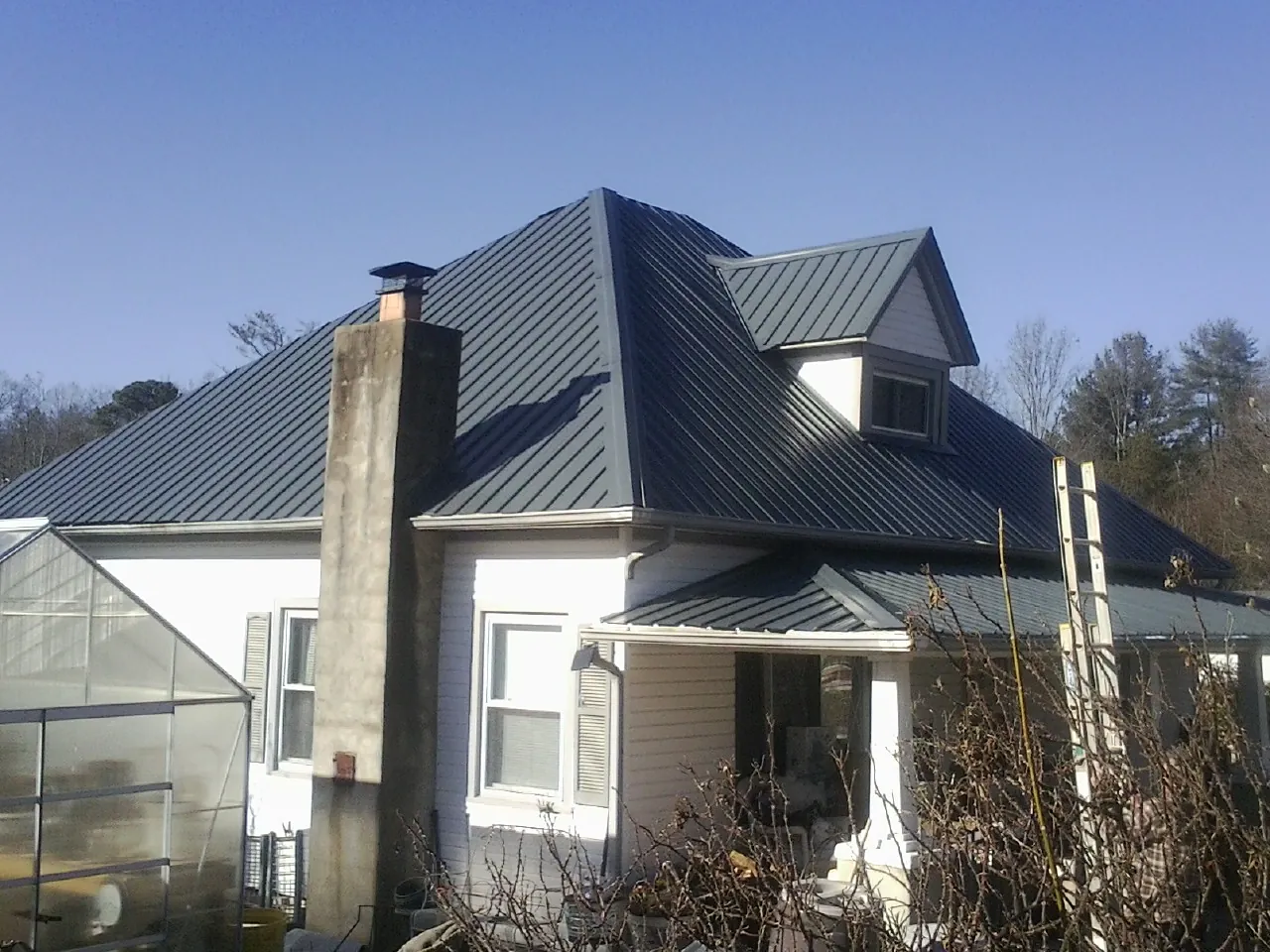 Dark blue standing seam metal roof on a white farmhouse with dormer — Slate & Tile Roof Repair by Roofing Brothers in Waterport