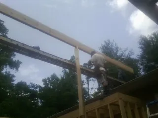 Carpenter setting a ridge beam over a new addition frame — Ice Dam Removal by Roofing Brothers in Waterport