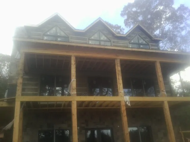 Dormers and porch framing on a large log home under construction — Roof Coating work by our crew in Waterport