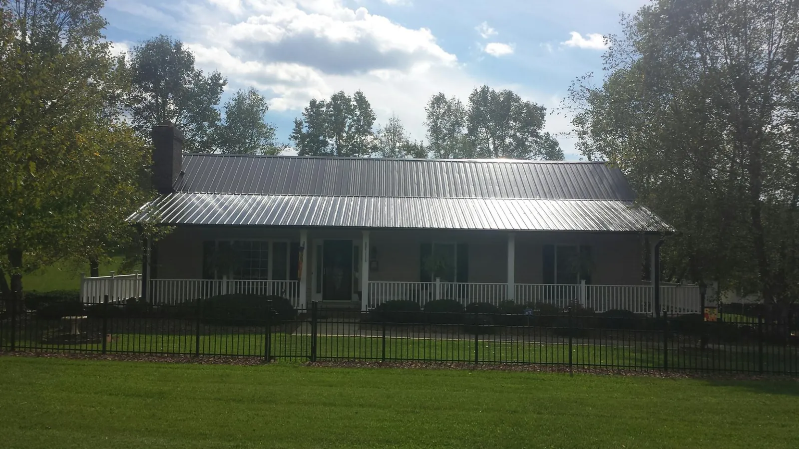 Gray metal roof on a brick ranch with a full width front porch — Gutter Guard Installation work by our crew in Waterport