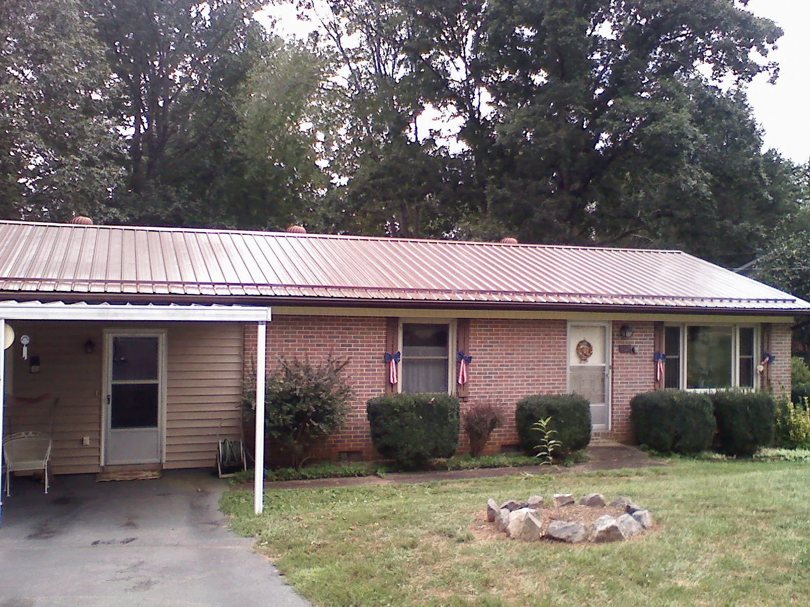 Bronze metal roof and carport on a brick ranch home — Roof Repair work by our crew in Waterport