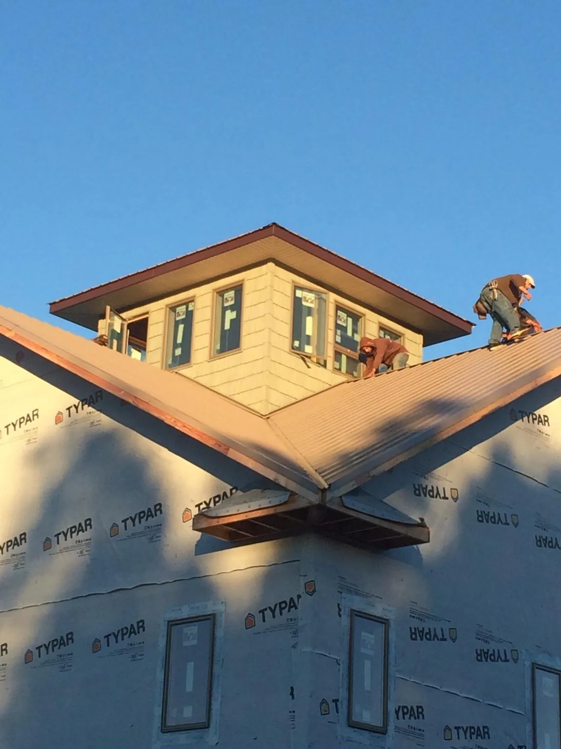 Roofers working around a rooftop cupola on a new metal roof at sunset — Roof Waterproofing in Waterport by Roofing Brothers